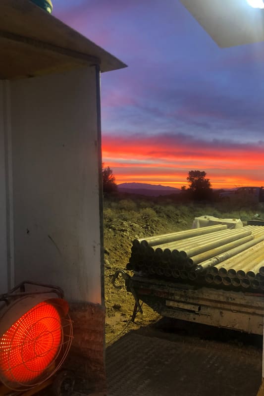 Sunrise over the mountains behind a trailer of drill rod at the site